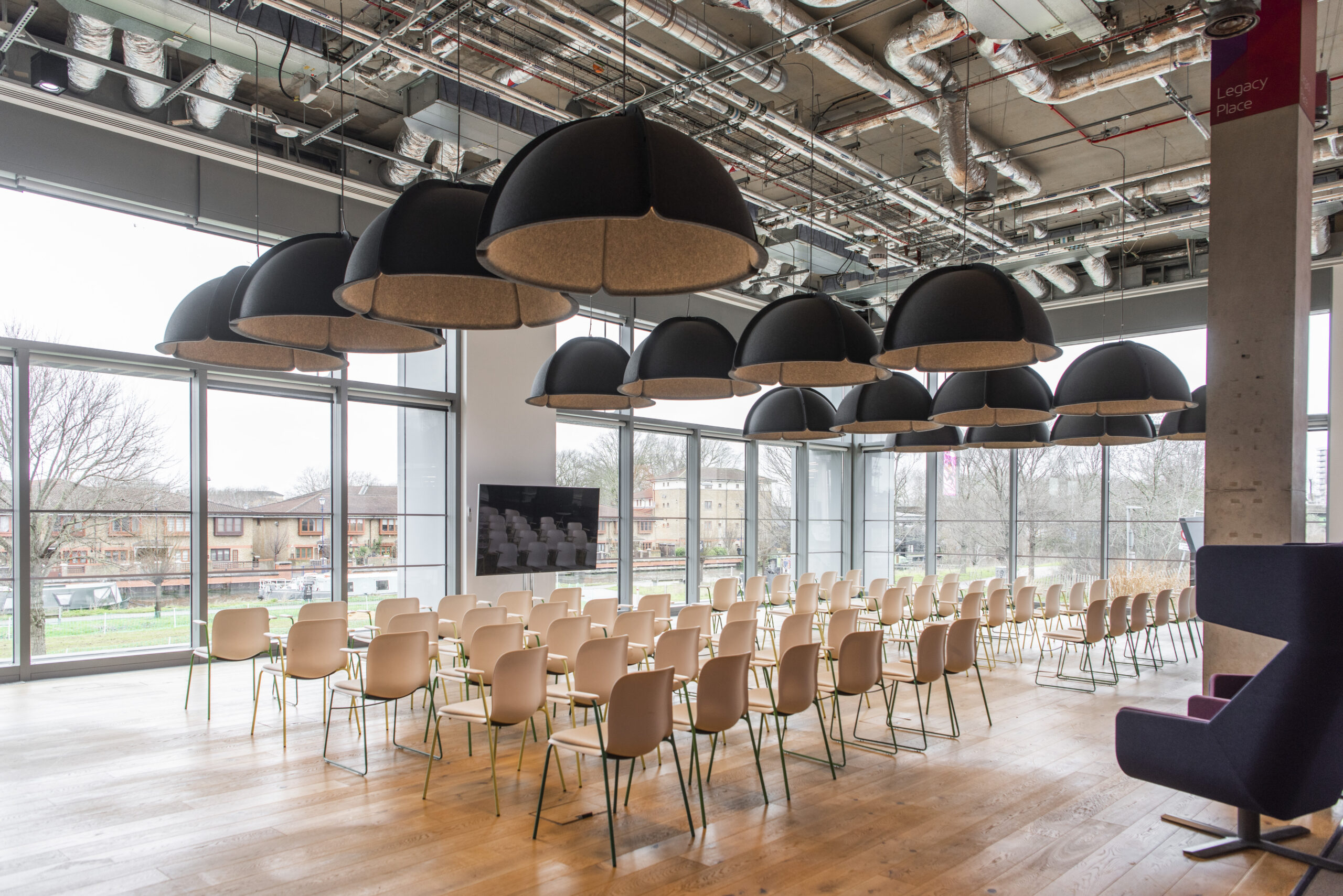 Image of event space with a large screen at the front and rows of empty chairs for an audience to sit in